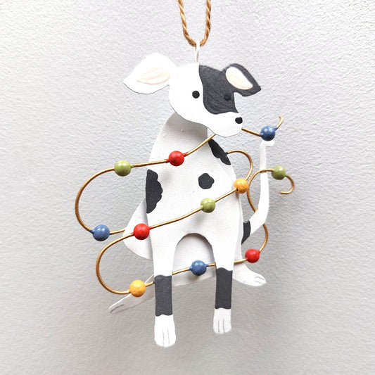 A tin spotty dog decoration with Christmas lights against a white background
