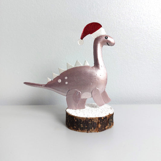 Decorative metal dinosaur figurine wearing a Santa hat on a white background