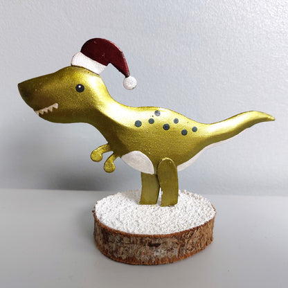 A metal T-Rex wearing a santa hat on a wooden base