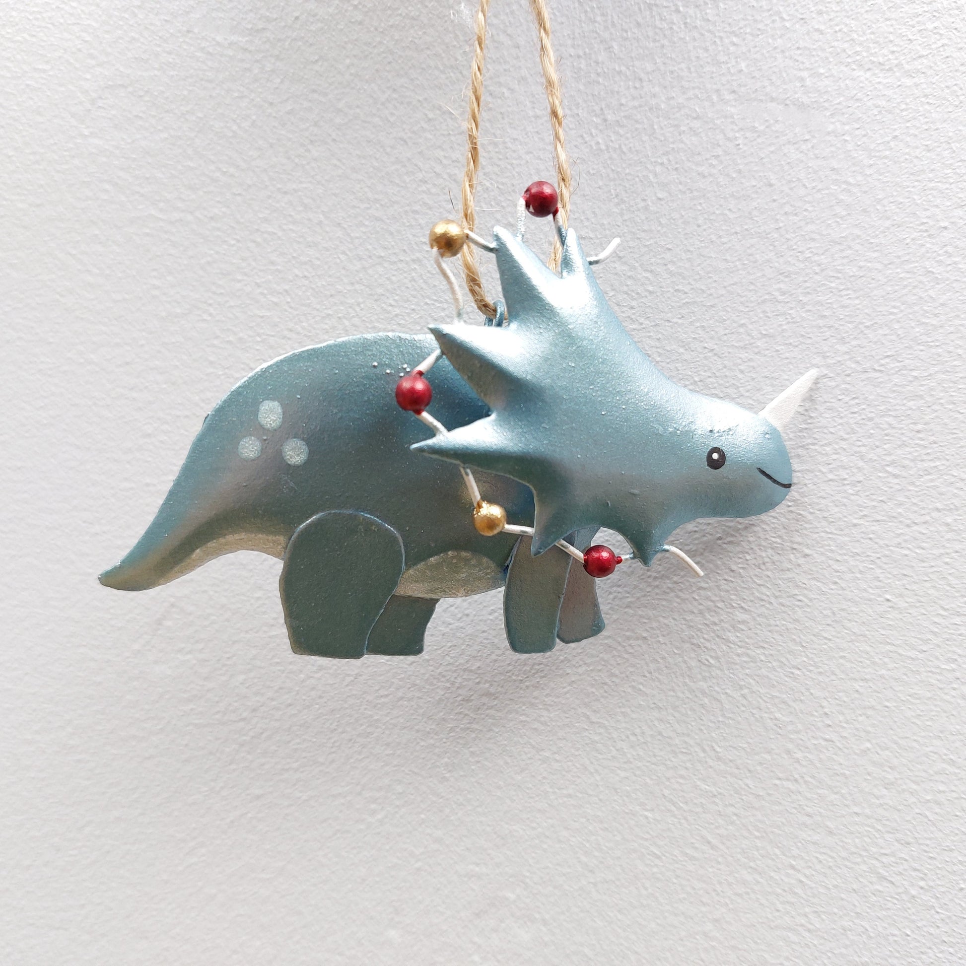 Decorative green dinosaur ornament with Christmas lights on a white background