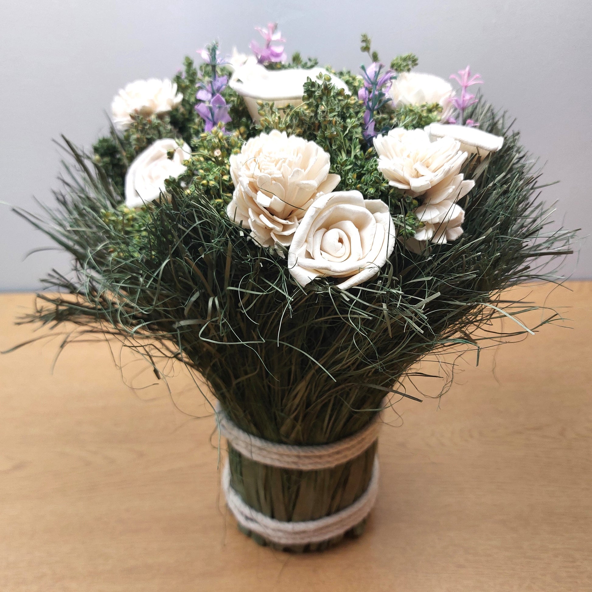 Dried Bouquet of white flowers with greenery on a wooden surface