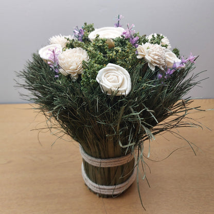 Bouquet of white and pink flowers in a tied bouquet on a wooden surface with a gray background