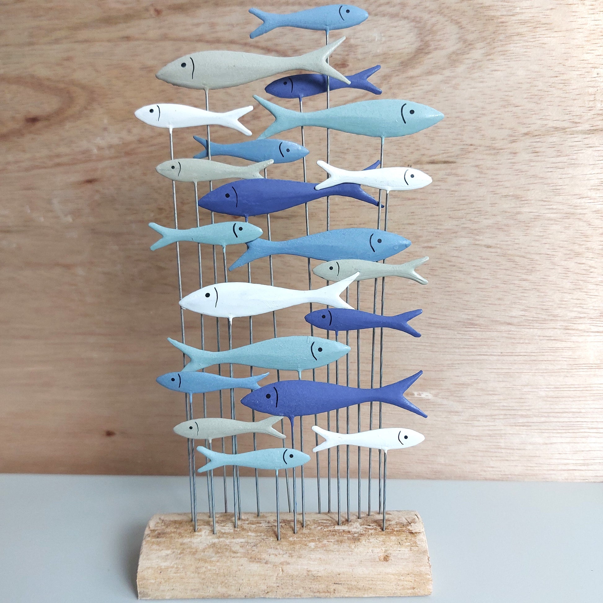 Decorative metal sculpture of fish on a wooden base against a wooden background