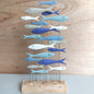 Decorative metal sculpture of fish on a wooden base against a wooden background