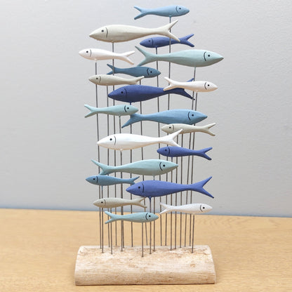 Decorative metal sculpture of colourful fish on a stand with a plain background