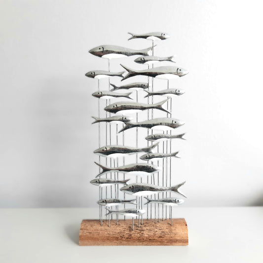 Decorative sculpture of fish on a wooden base against a white background