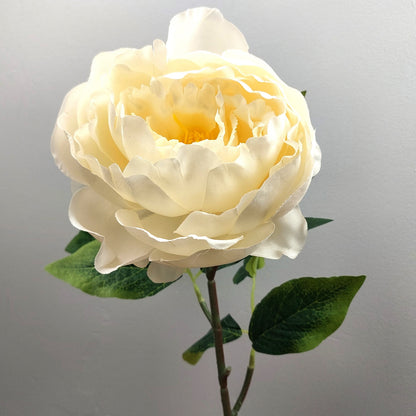 Artificial Ivory Peony flower with green leaves on a gray background