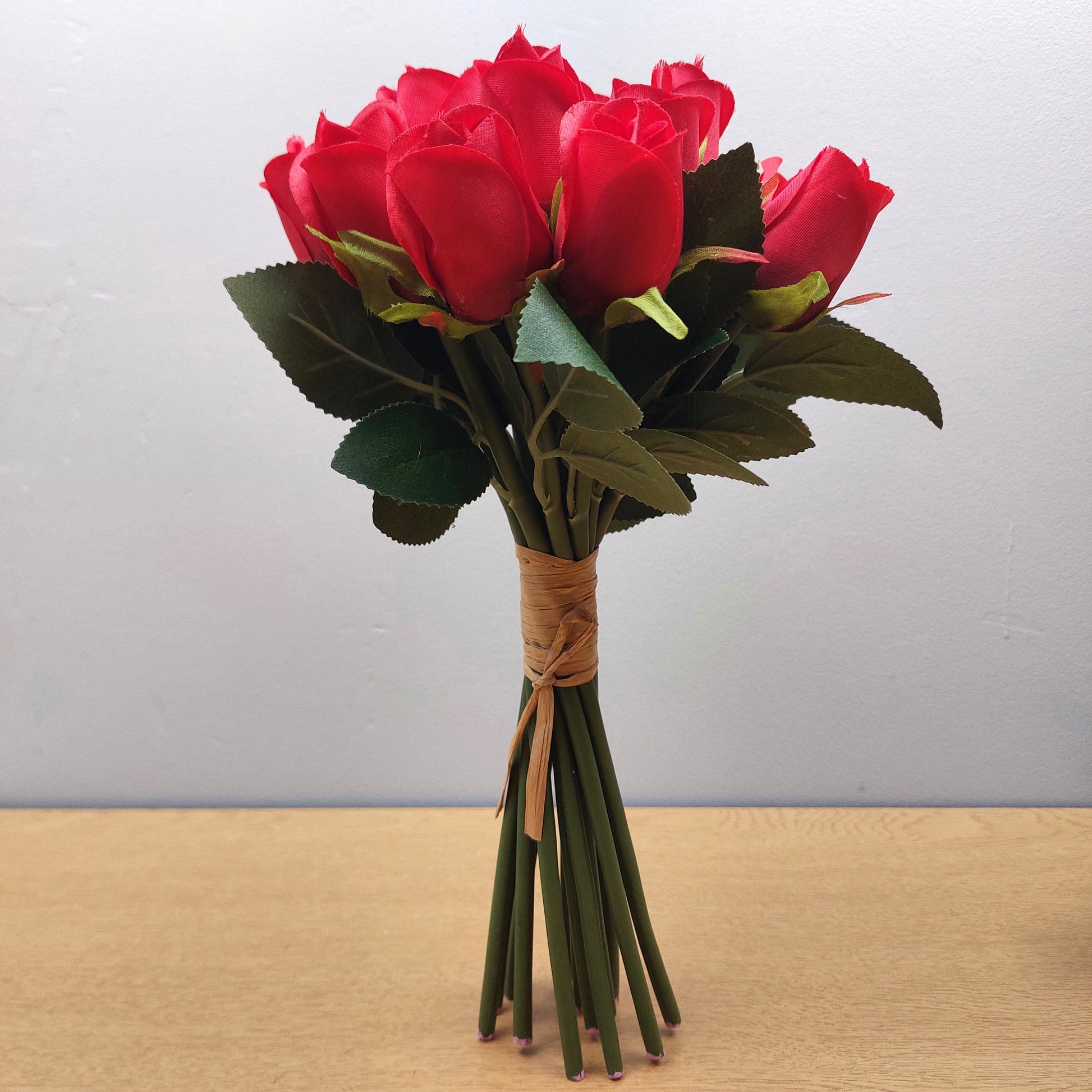 A bunch of Artificial Red Roses against a pale background