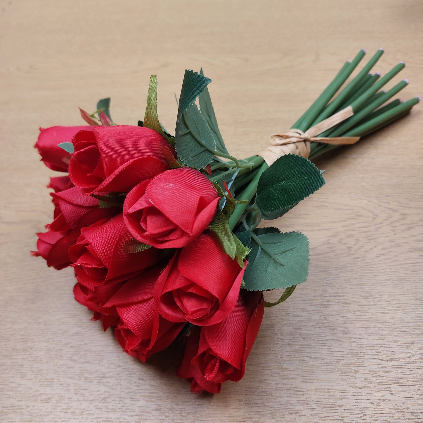 A bunch of Artificial Roses laying down against a wooden background