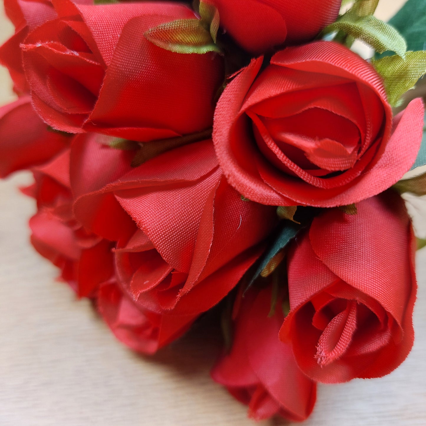 A close up of Artificial Red Roses against a wooden background