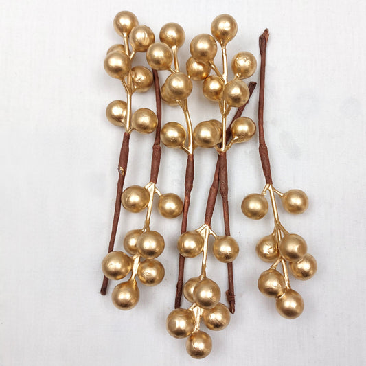 Gold berry picks on a white background