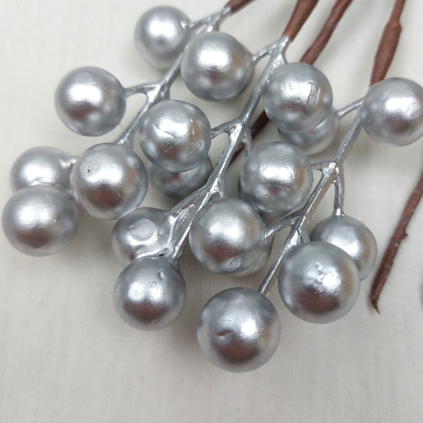 Decorative branch with silver berries on a plain background