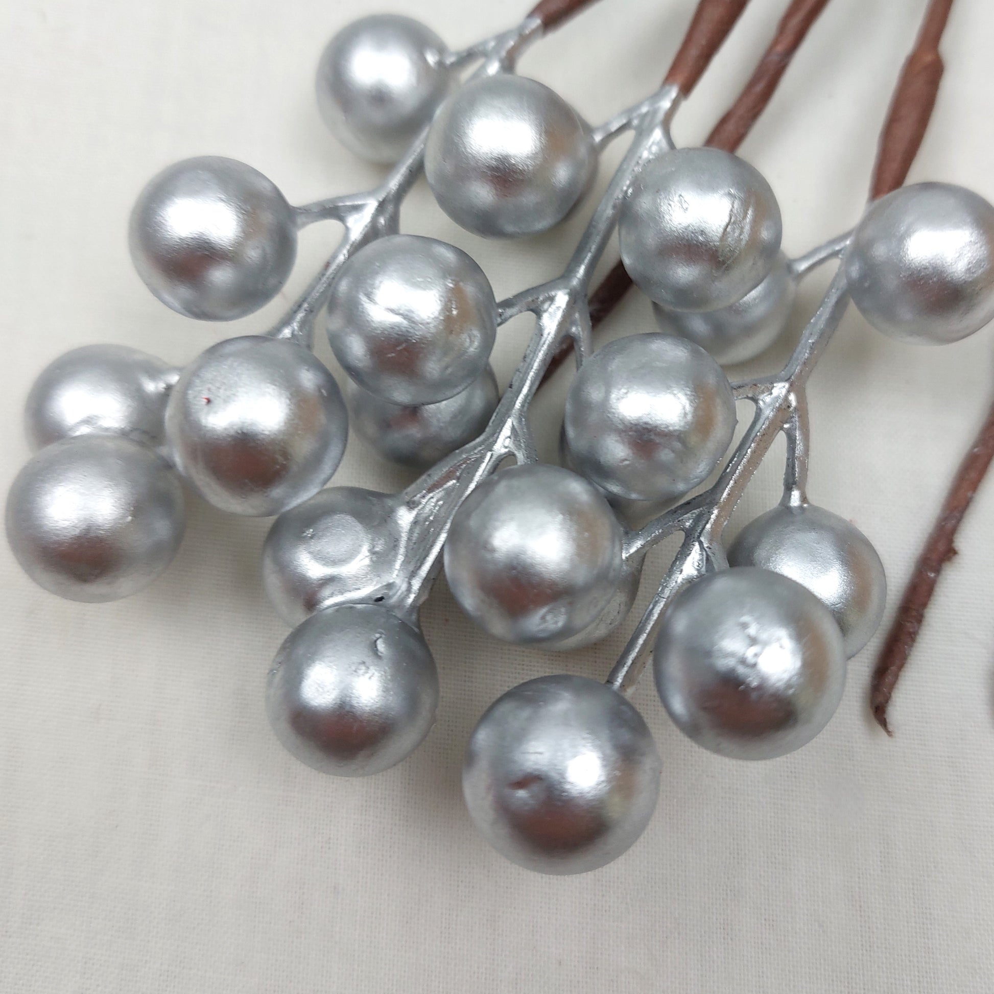 Decorative branch with silver berries on a plain background