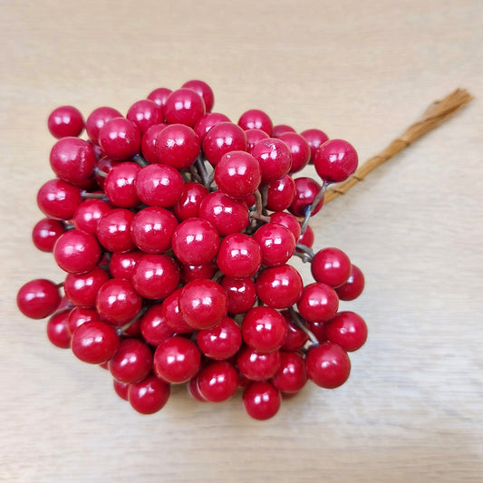 Bunch of artificial red berries on a wooden surface