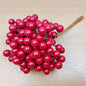 Bunch of artificial red berries on a wooden surface