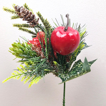 Decorative artificial arrangement with red apples, berries and greenery on a white background