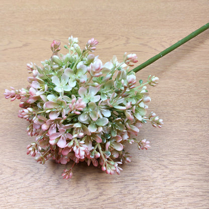 An artificial Pink and Green Allium Flower against a wooden background