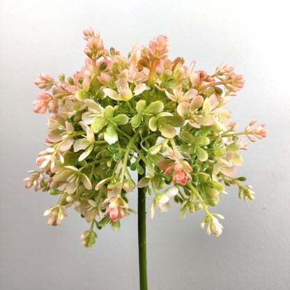 An artificial Pink and Green Allium flower and stem against a pale background
