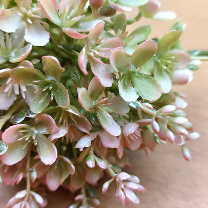 Close-up of pink and green artificial alliumflowers on a wooden surface