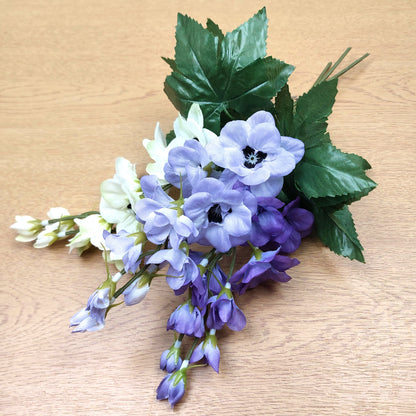 Artificial Delphinium flower arrangement with purple and white flowers on a wooden surface