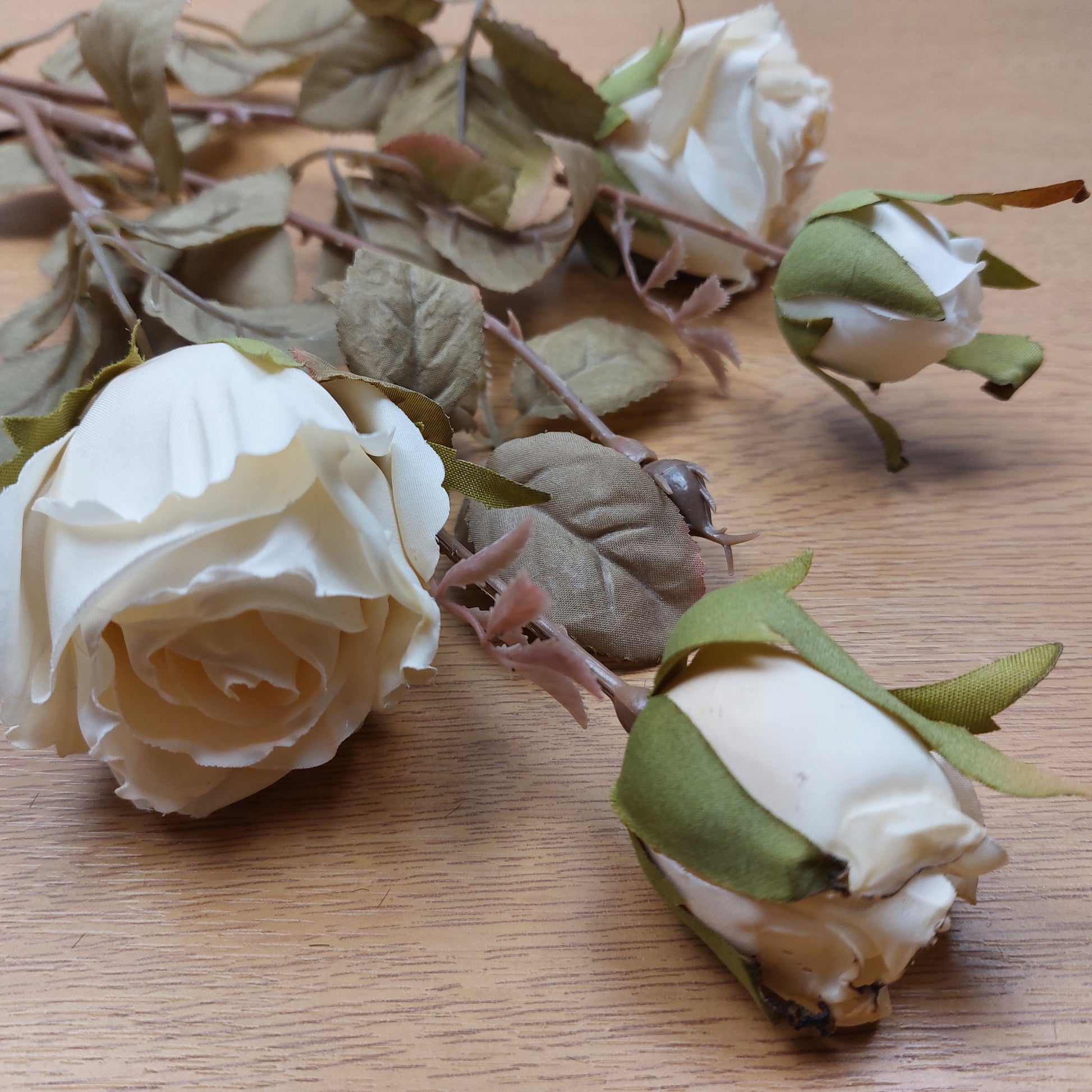 An artificial Cream Cabbage Rose bunch laying down on a wooden surface