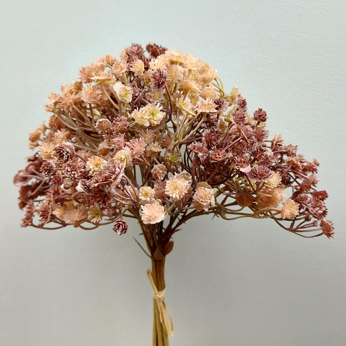 Artificial Bouquet of dried look flowers with a light background