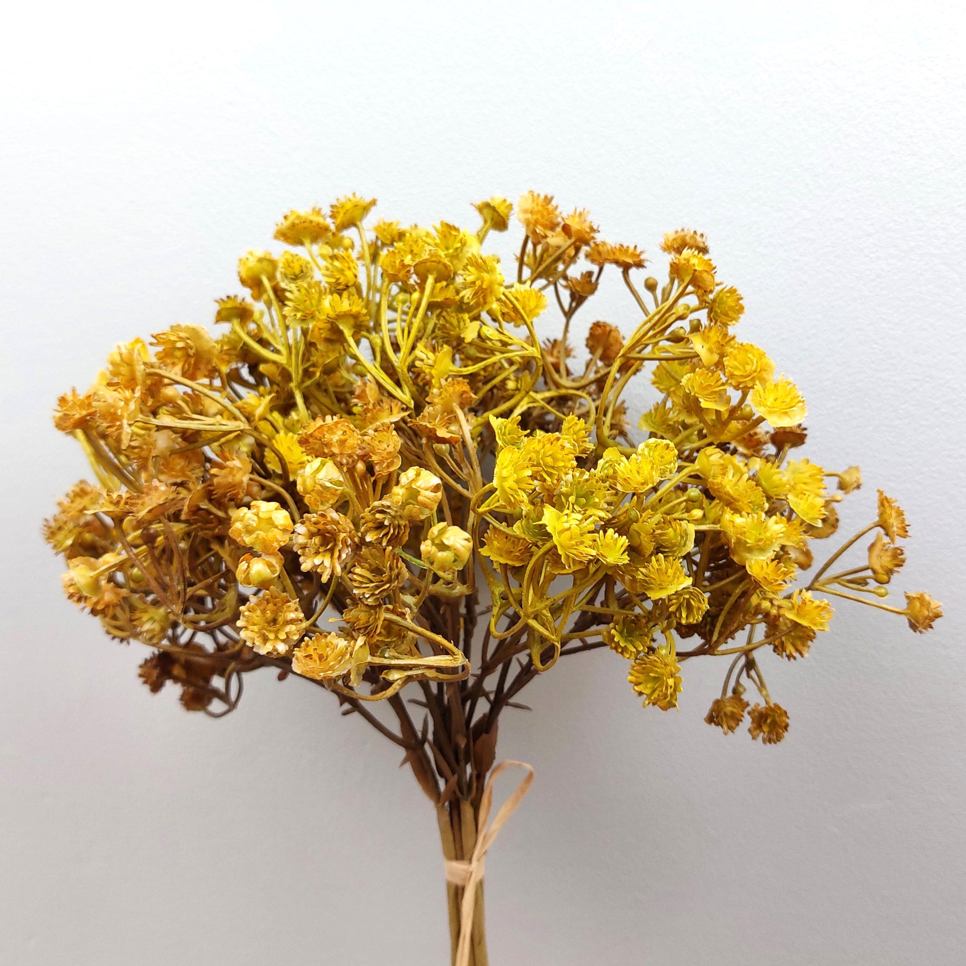 Artificial Bouquet of dried look yellow flowers on a light gray background