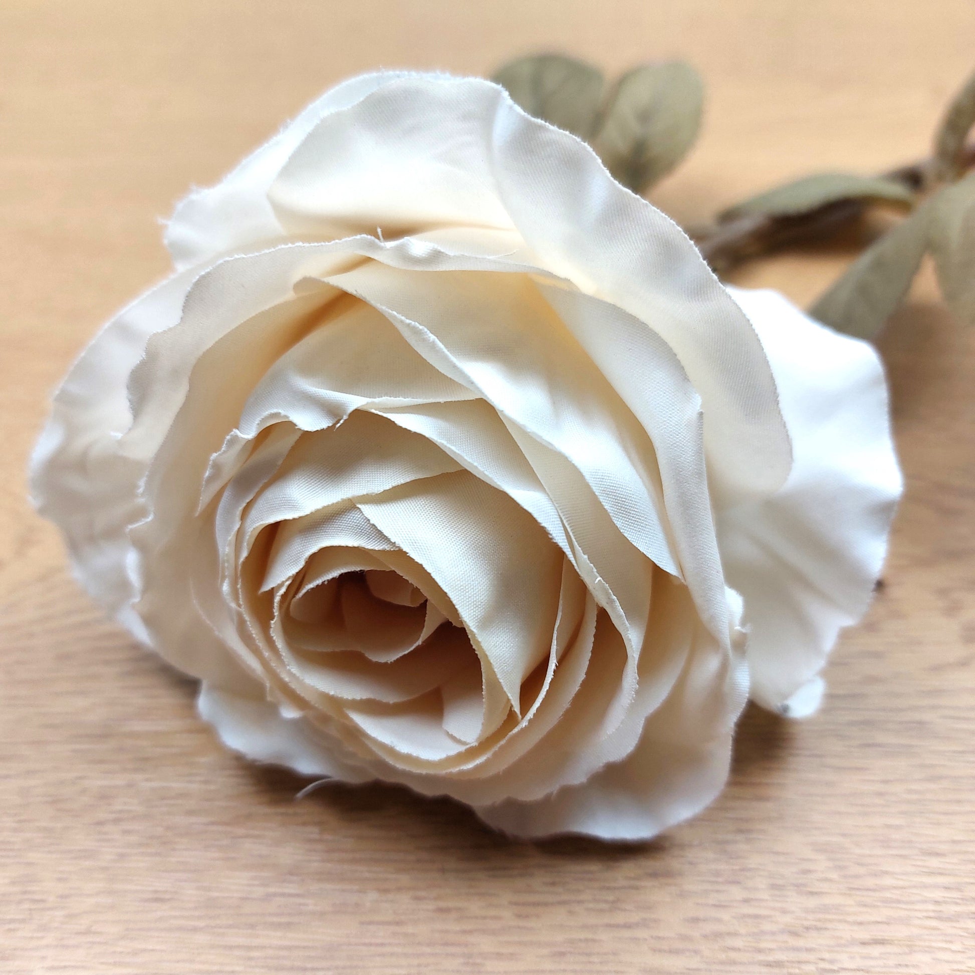 Close-up of a cream dried look artificial rose on a wooden surface