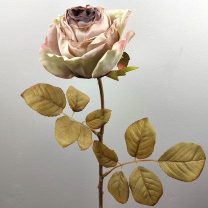 Artificial cabbage rose flower arrangement with a mauve and pink rose and green leaves on a light gray background