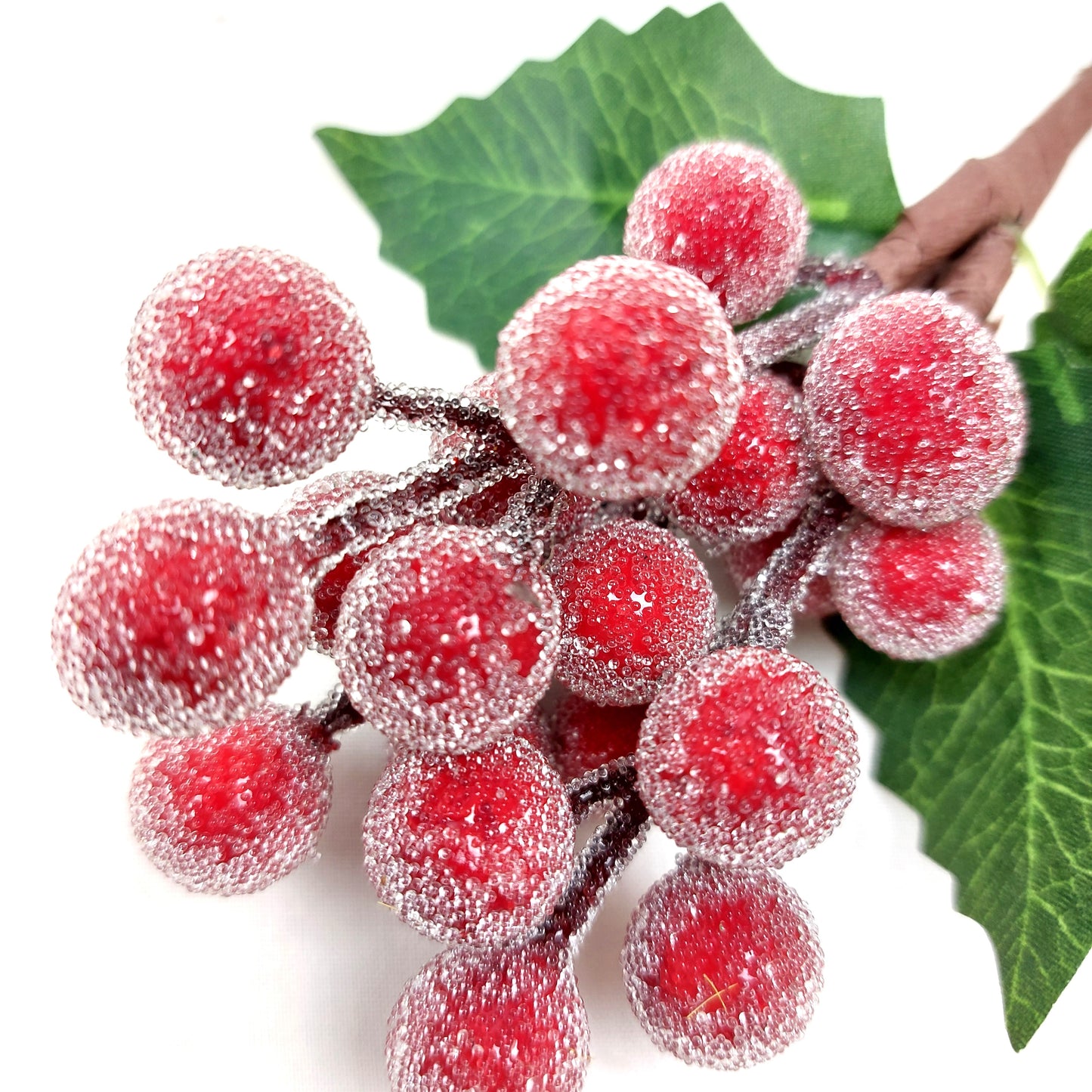 Close up of artificial Red berries with green leaves on a white background