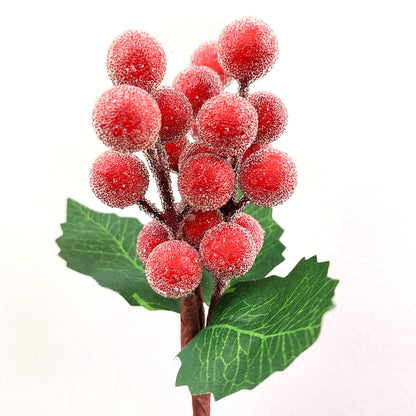 Artificial red berry branch with green leaves on a white background