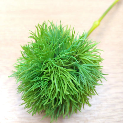 Close up of an artificial Green Trick Dianthus Pom Pom decorative ball with a textured surface on a light wooden background