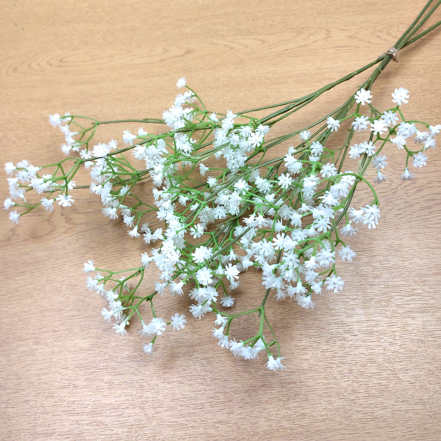 A bunch of artificial White Gypsophila against a wooden background