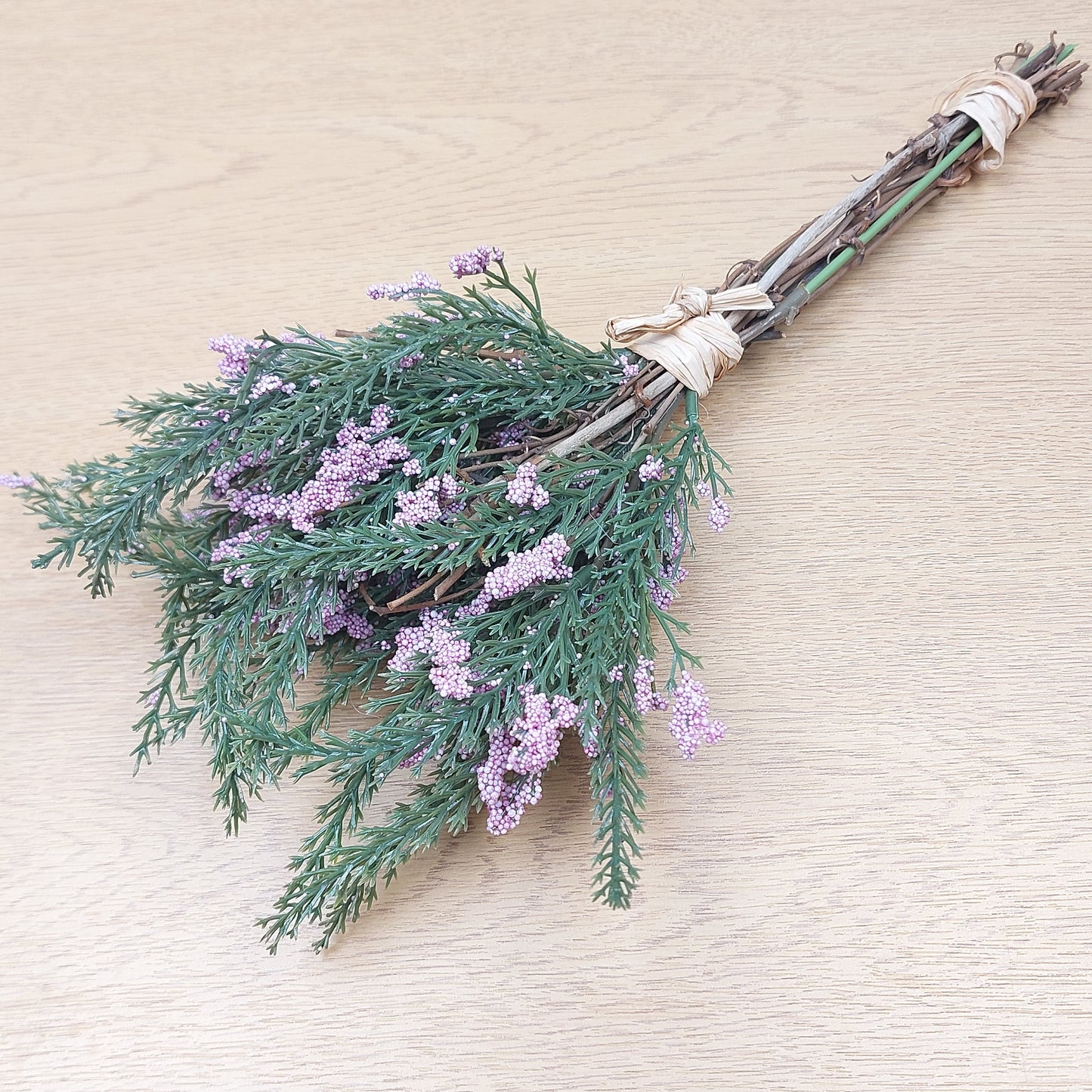 Decorative Faux Heather broom with greenery and lavender flowers on a beige background