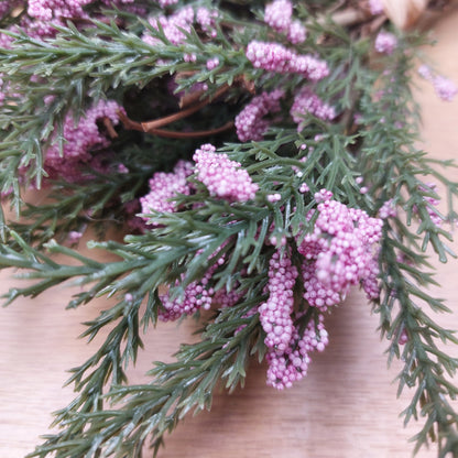 Close-up of artificial green heather leaves and lilac flowers on a blurred background