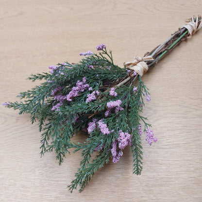 An artificial Heather Bouquet of lavender flowers and greenery tied with  raffia twine on a wooden background