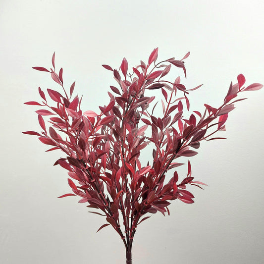 Artificial red and burgundy huckleberry leaf branch on a light gray background
