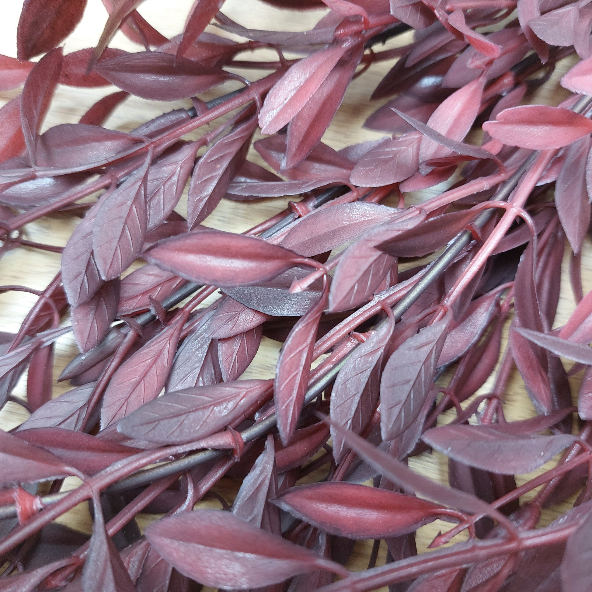 Close-up of red artificial huckleberry leaves on a wooden surface