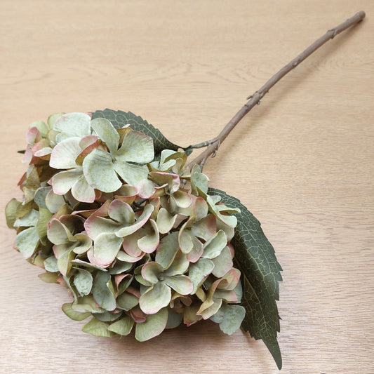 Artificial hydrangea flower branch on a wooden surface