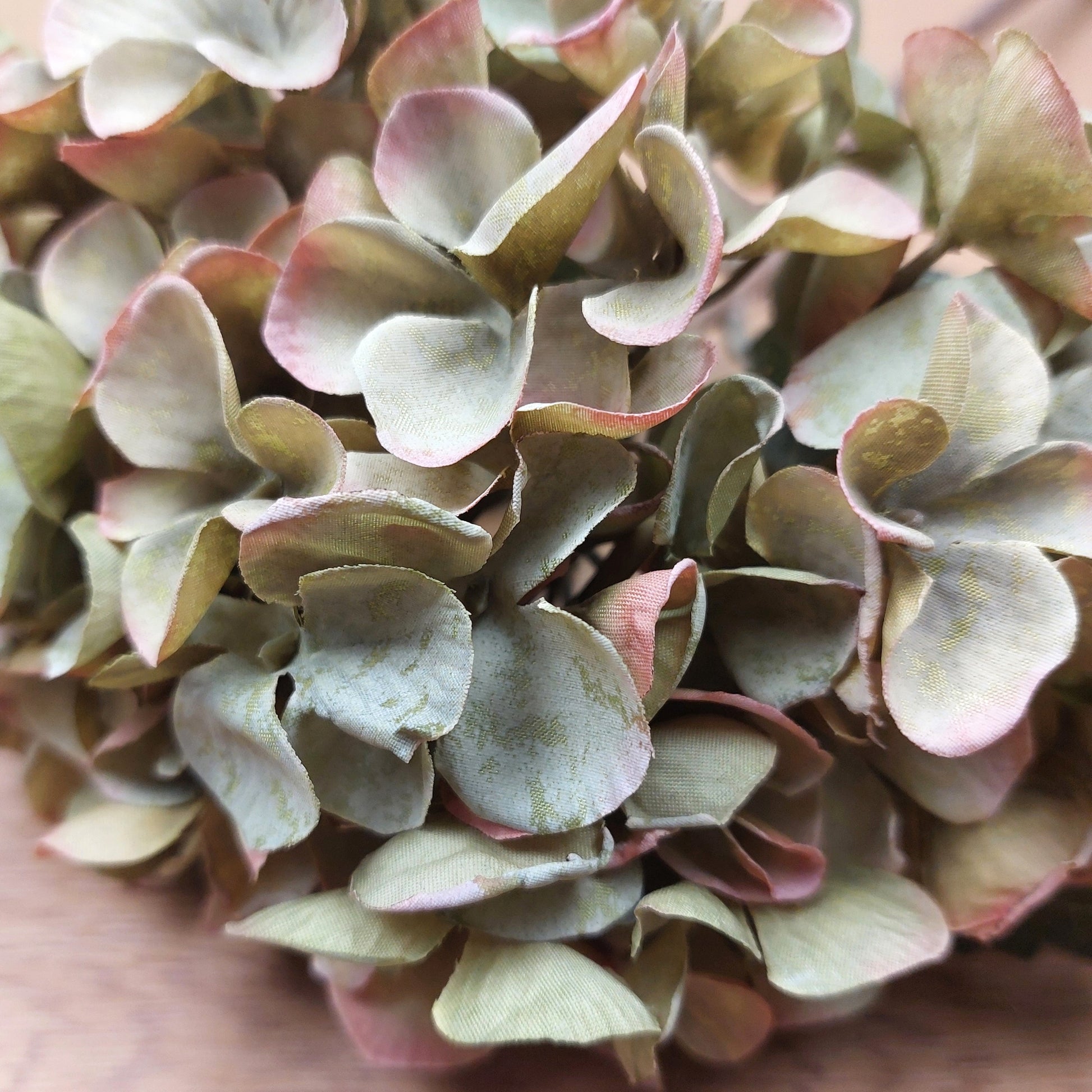 Close-up of artificial hydrangea flowers with pink and green hues.