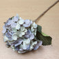 Artificial lilac hydrangea flower arrangement on a wooden surface