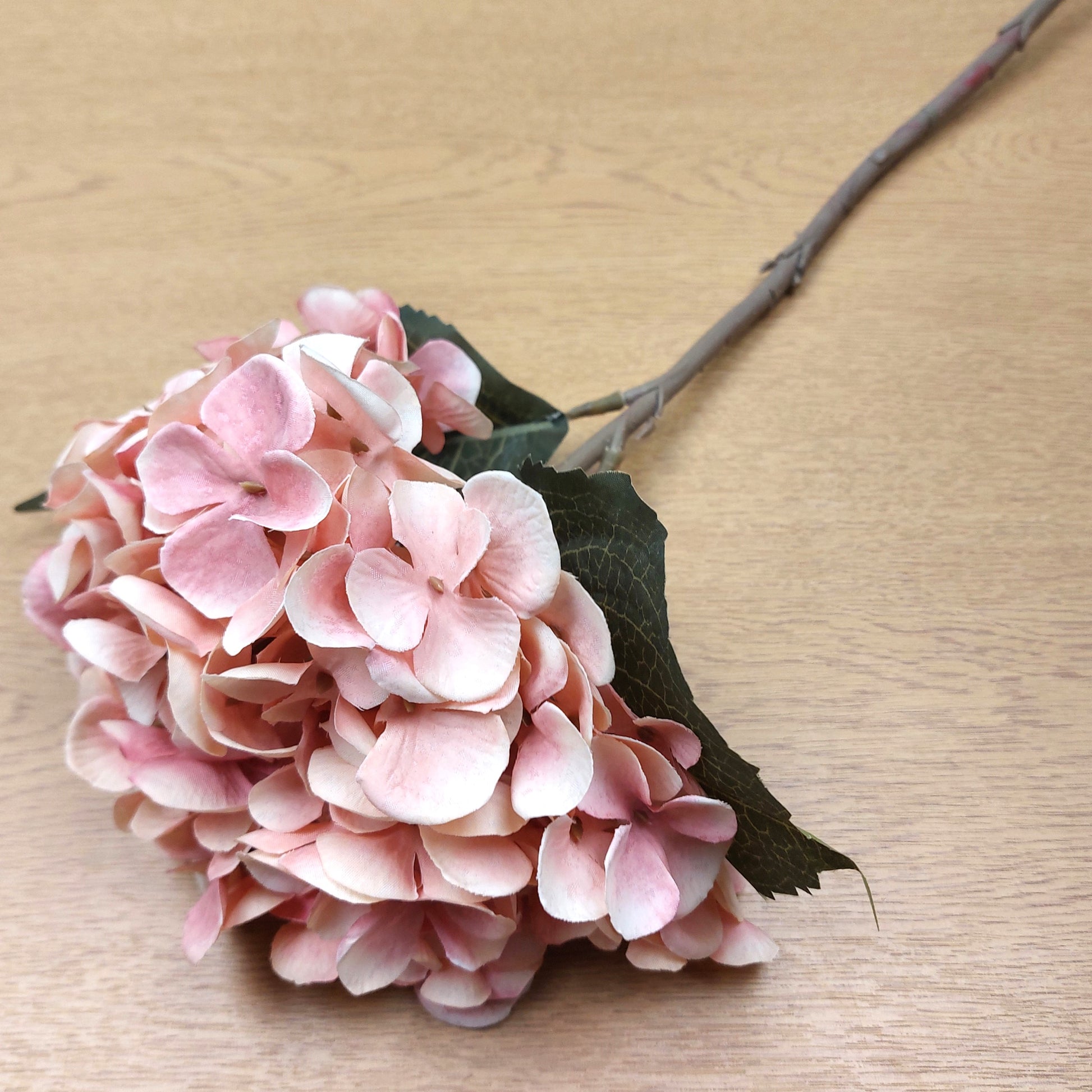 Artificial Pink hydrangea flower on a wooden surface