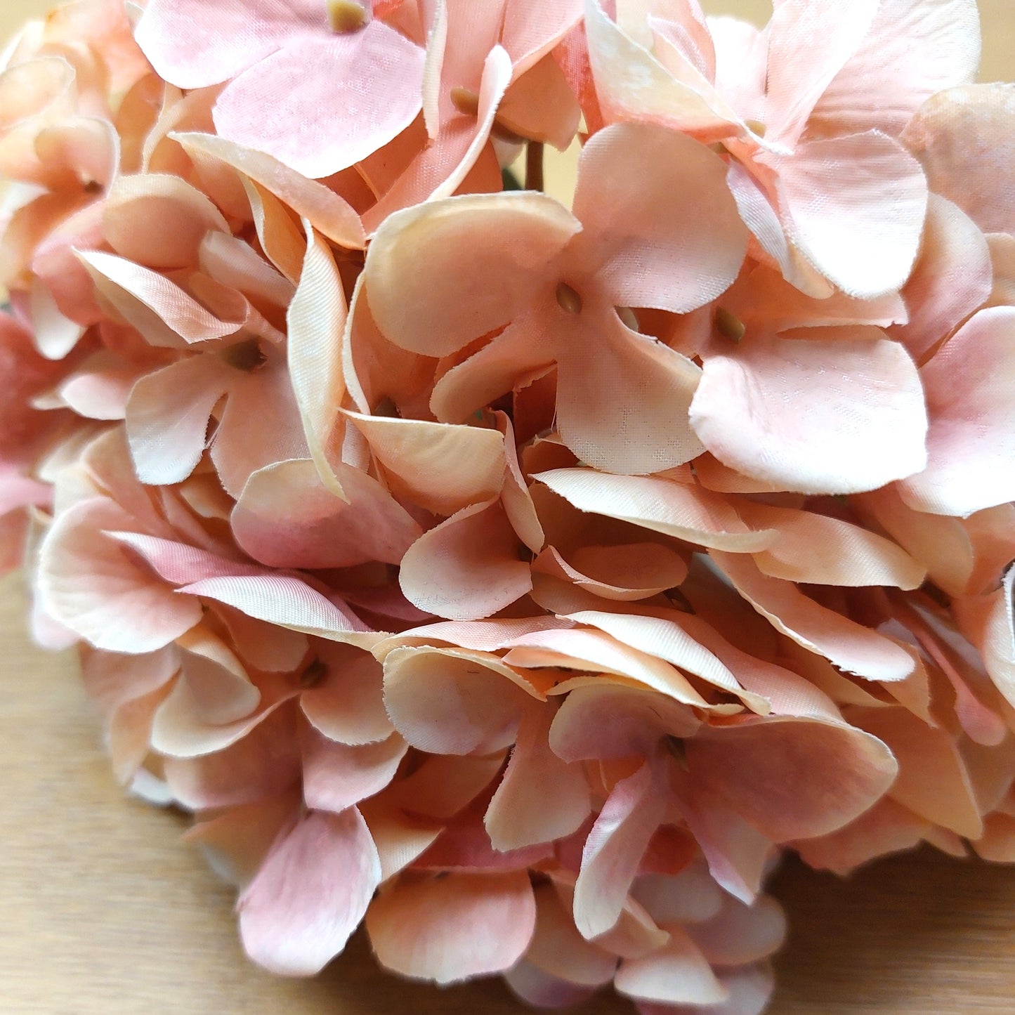 Close-up of artificial pink hydrangea flowers on a wooden surface