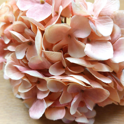 Close-up of artificial pink hydrangea flowers on a wooden surface