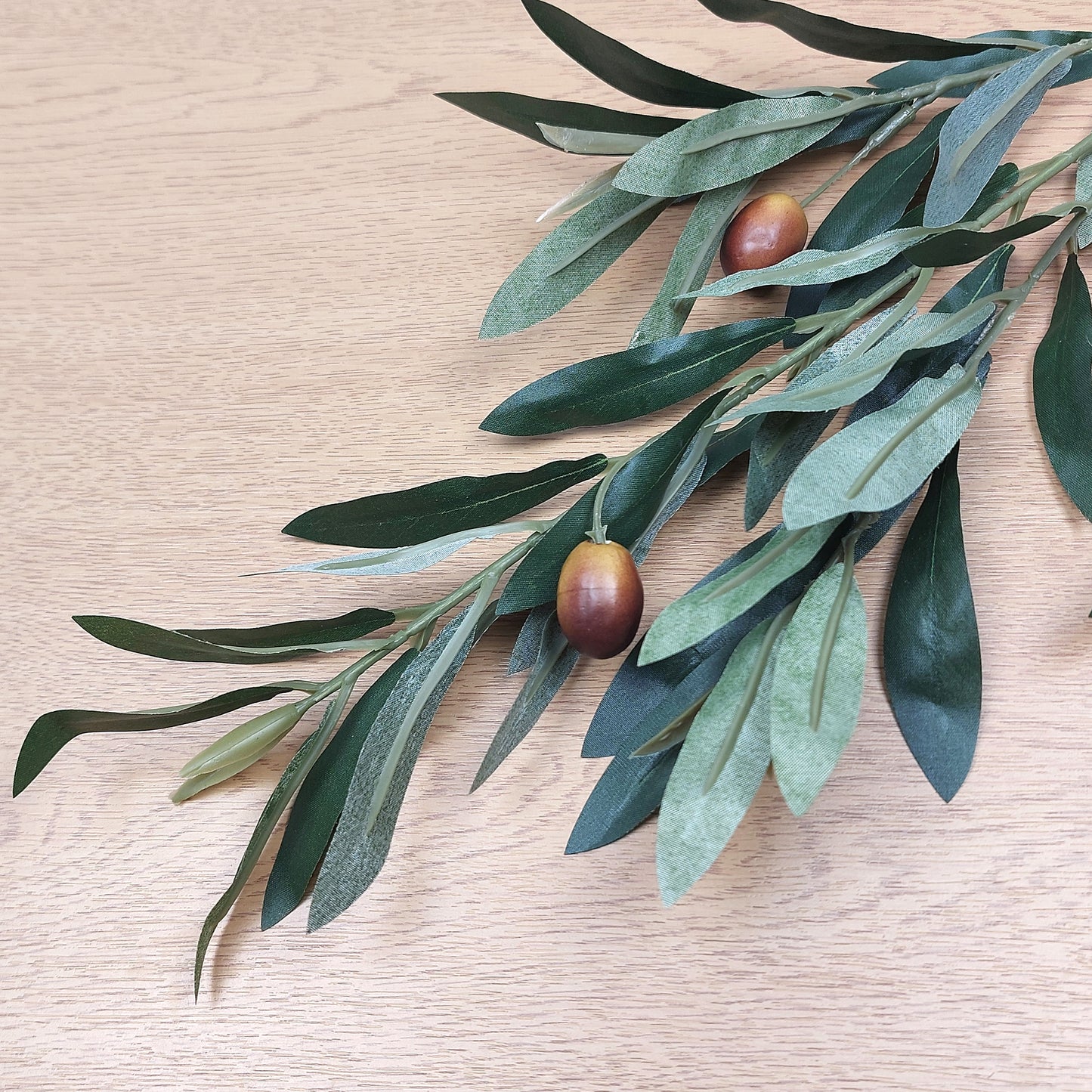 Artificial Olive branch with brown olives on a wooden surface