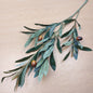Artificial Olive branch with green leaves and brown olives on a wooden surface