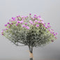 A bunch of artificial lilac open gypsophila flowers with green leaves and purple flowers, tied together at the bottom.