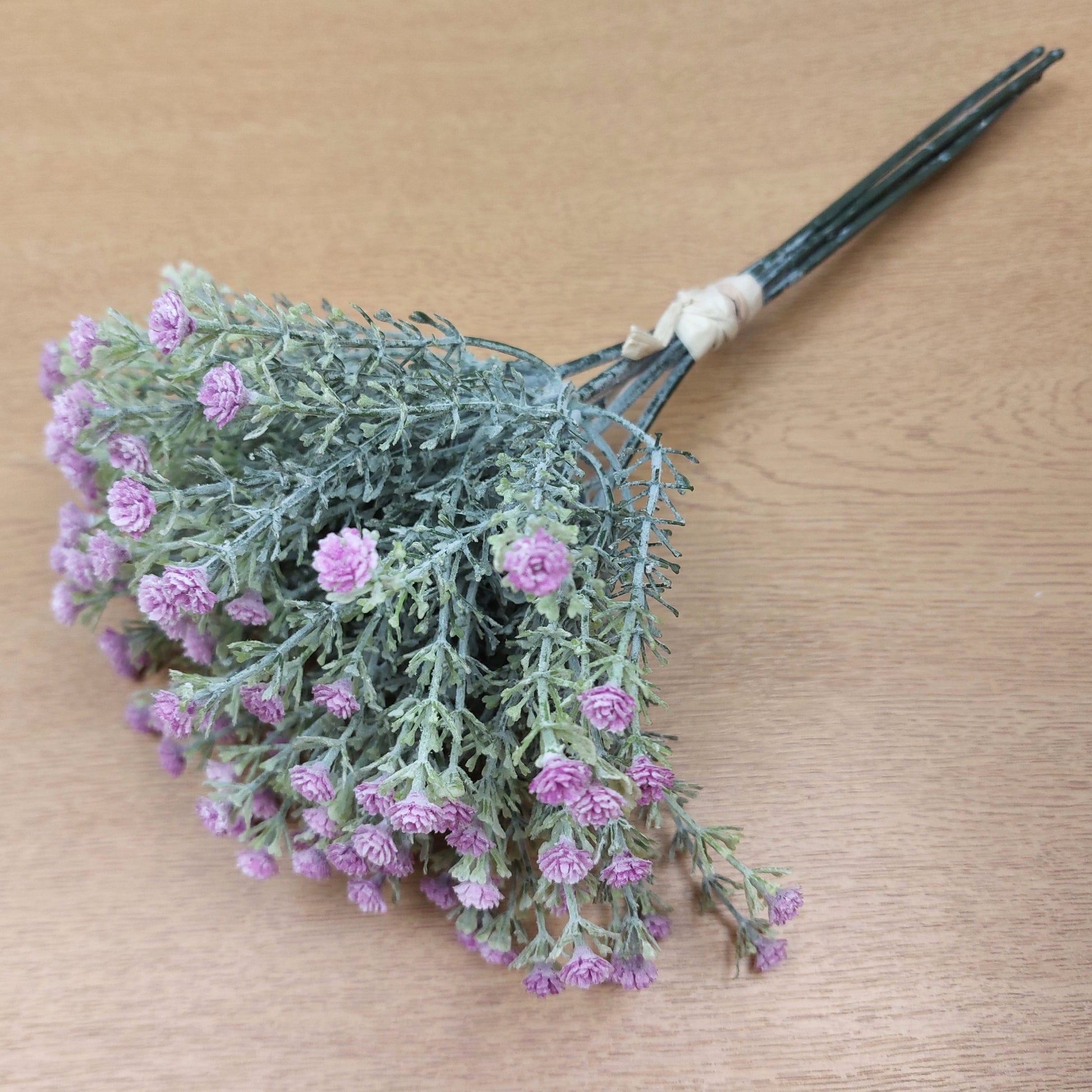 Bouquet of artificial flowers with pink blossoms on a wooden surface