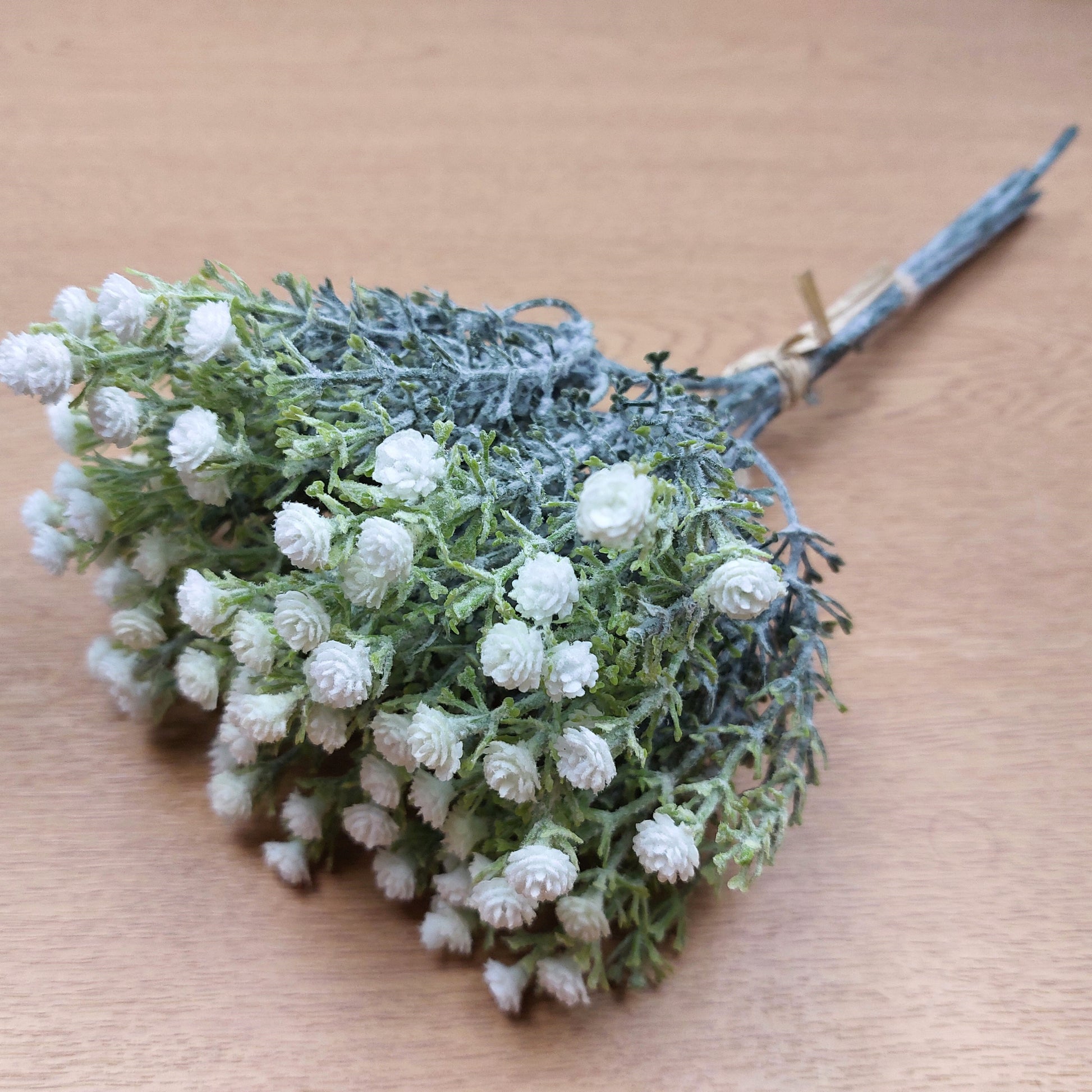 Bouquet of small white artificial Gyp flowers on a wooden surface