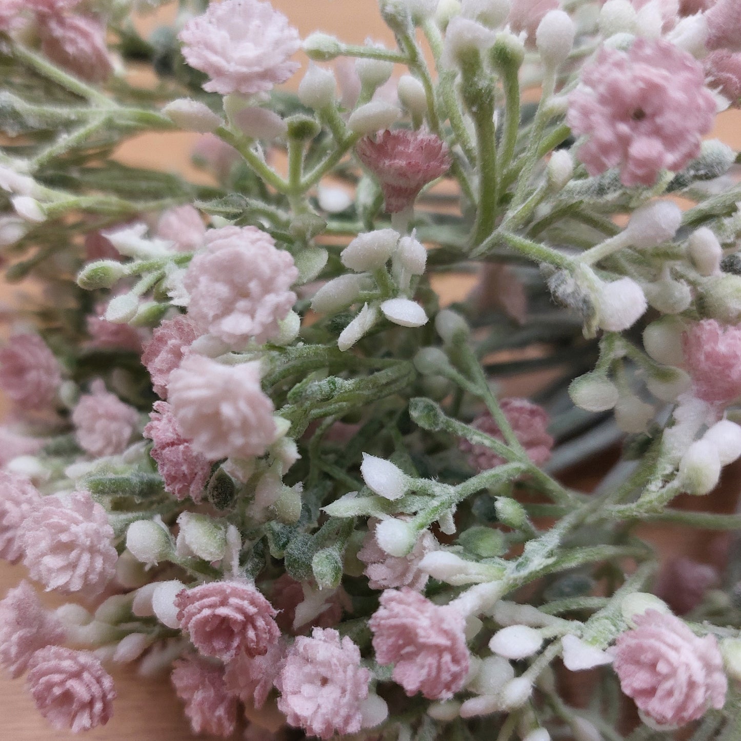 A close up of artificial pastel pink open Gyp with White Buds